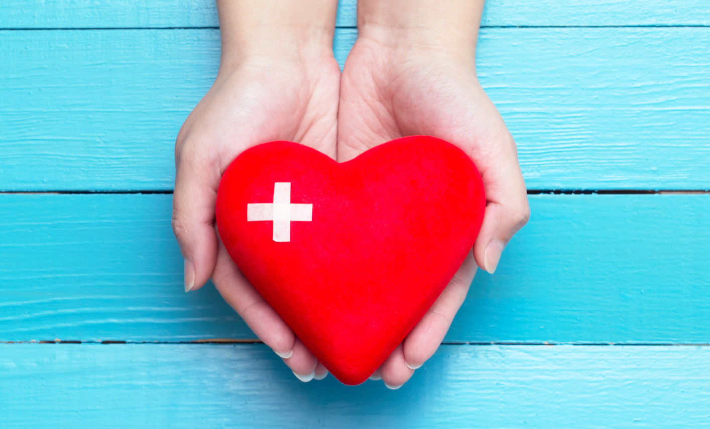 ein in Händen gehaltenes Herz mit Gesundheitssymbol darauf